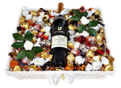סלסילה לבנה המכילה מוצרים טעימים באריזות בצבעים לבן, זהב ושחור, בצרוף בקבוק יין.